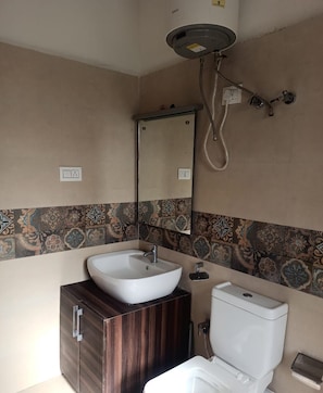 A bathroom with a white sink, a mirror, a toilet, and a shower head. - Mountain Retreat (Leh)