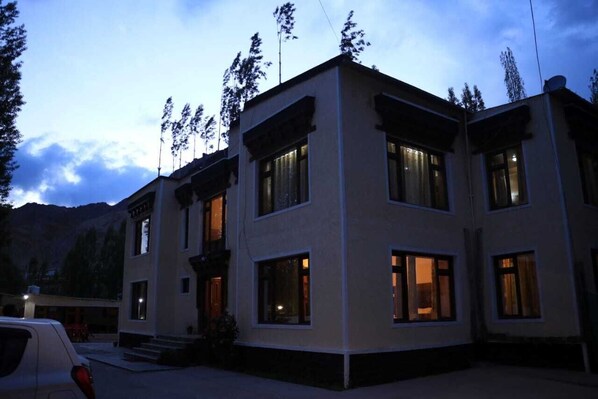 A two-story building with large windows and a balcony, surrounded by mountains. - Mountain Retreat (Leh)