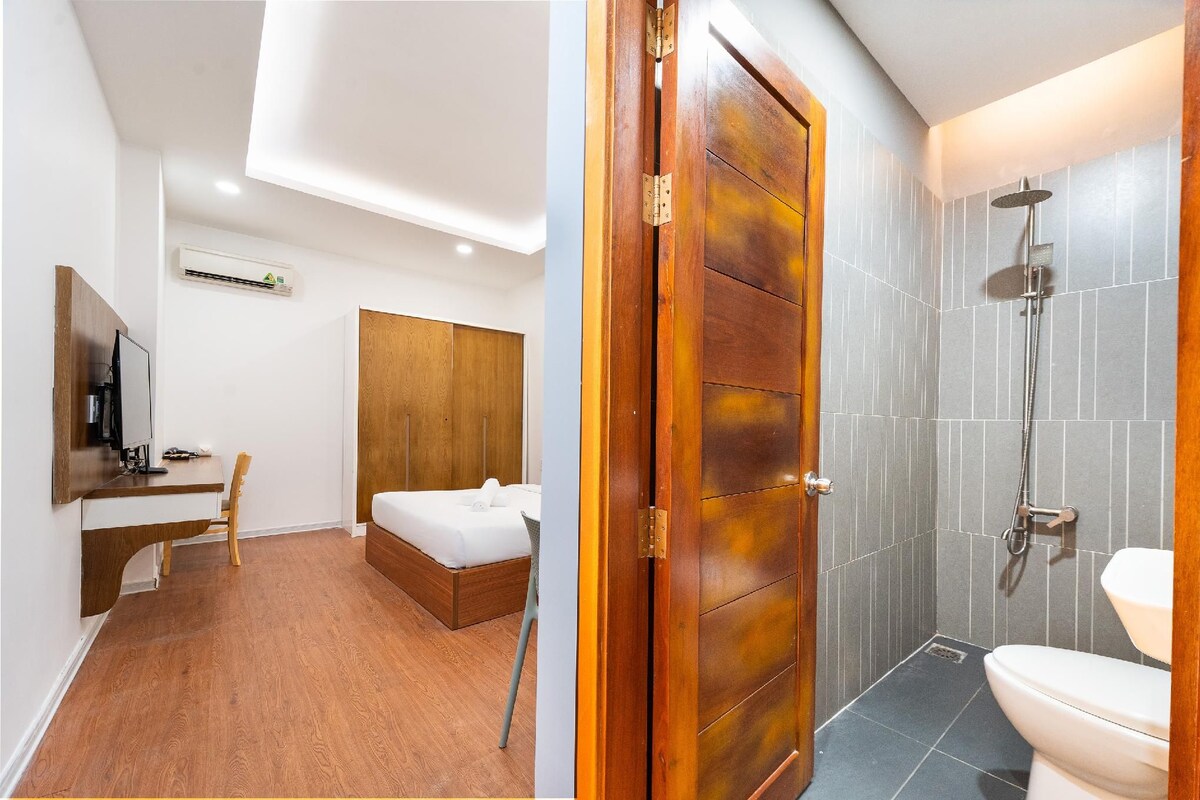 Une chambre d’hôtel comprenant un lit, un bureau, une chaise, une armoire et une salle de bain avec douche et toilettes.