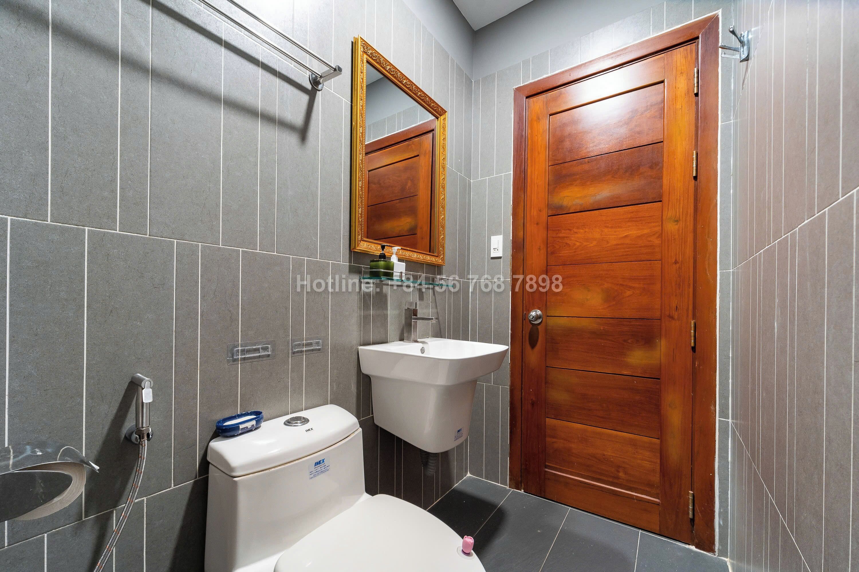A bathroom with a wooden door, a sink, and a toilet.