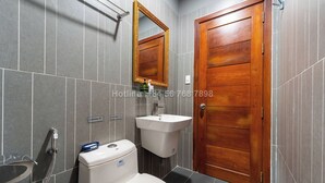 A bathroom with a wooden door, a sink, and a toilet. - TagoAmber (Ho Chi Minh City)