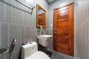Ein Badezimmer mit Holztür, Waschbecken und Toilette.