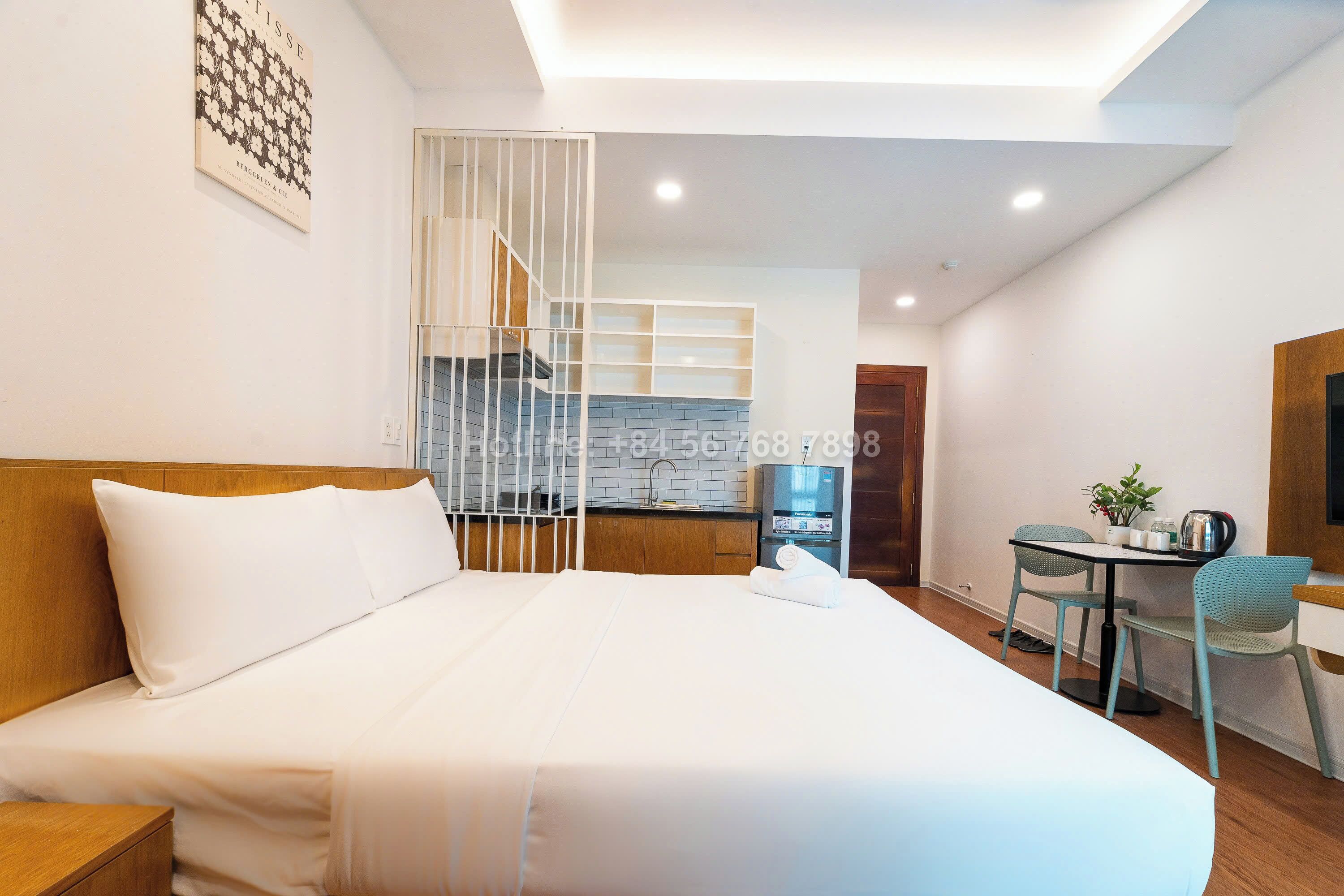 Een hotelkamer met een groot bed, een bureau met twee stoelen, een kitchenette en een trap.