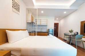 A hotel room with a large bed, a desk with two chairs, a kitchenette, and a staircase. - TagoAmber (Ho Chi Minh City)