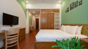 A bedroom with a bed, a desk, a chair, a television, and a bookshelf.