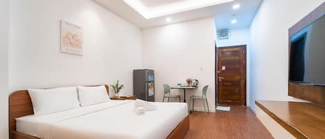 A hotel room with a bed, a desk, a chair, a television, and a door.