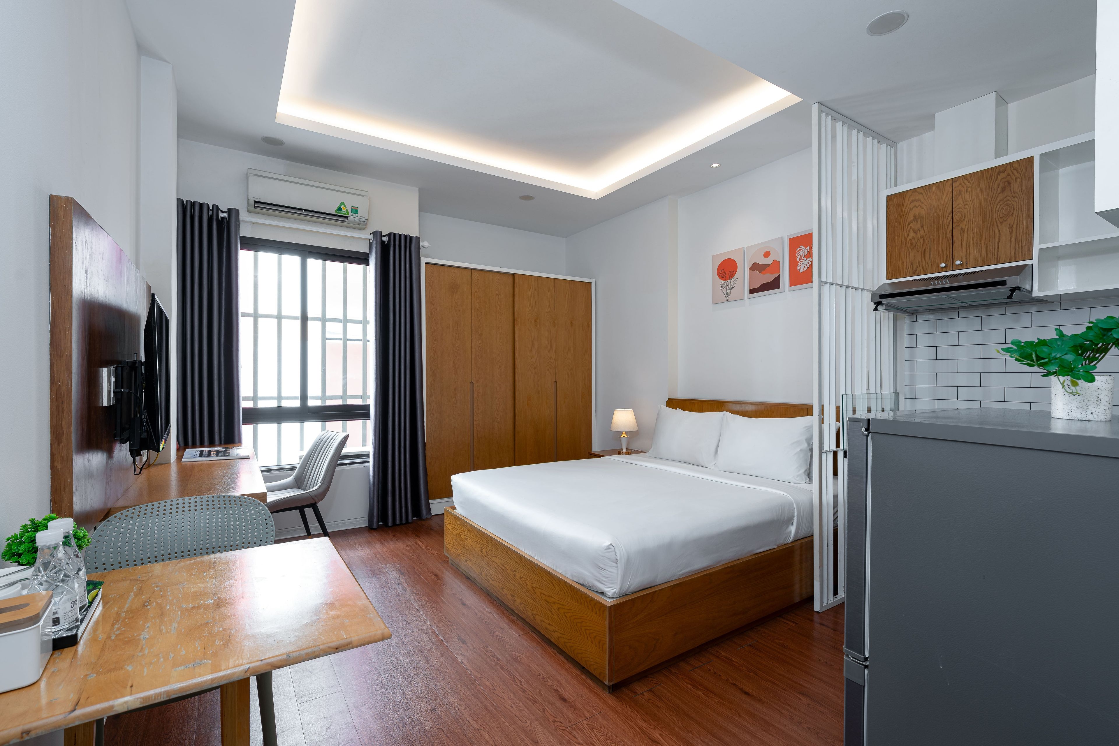 Una moderna camera d'albergo con un letto, una scrivania, una sedia, una TV e un angolo cottura.