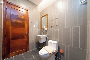 A bathroom with a wooden door, a white sink, and a toilet. - TagoAmber (Ho Chi Minh City)