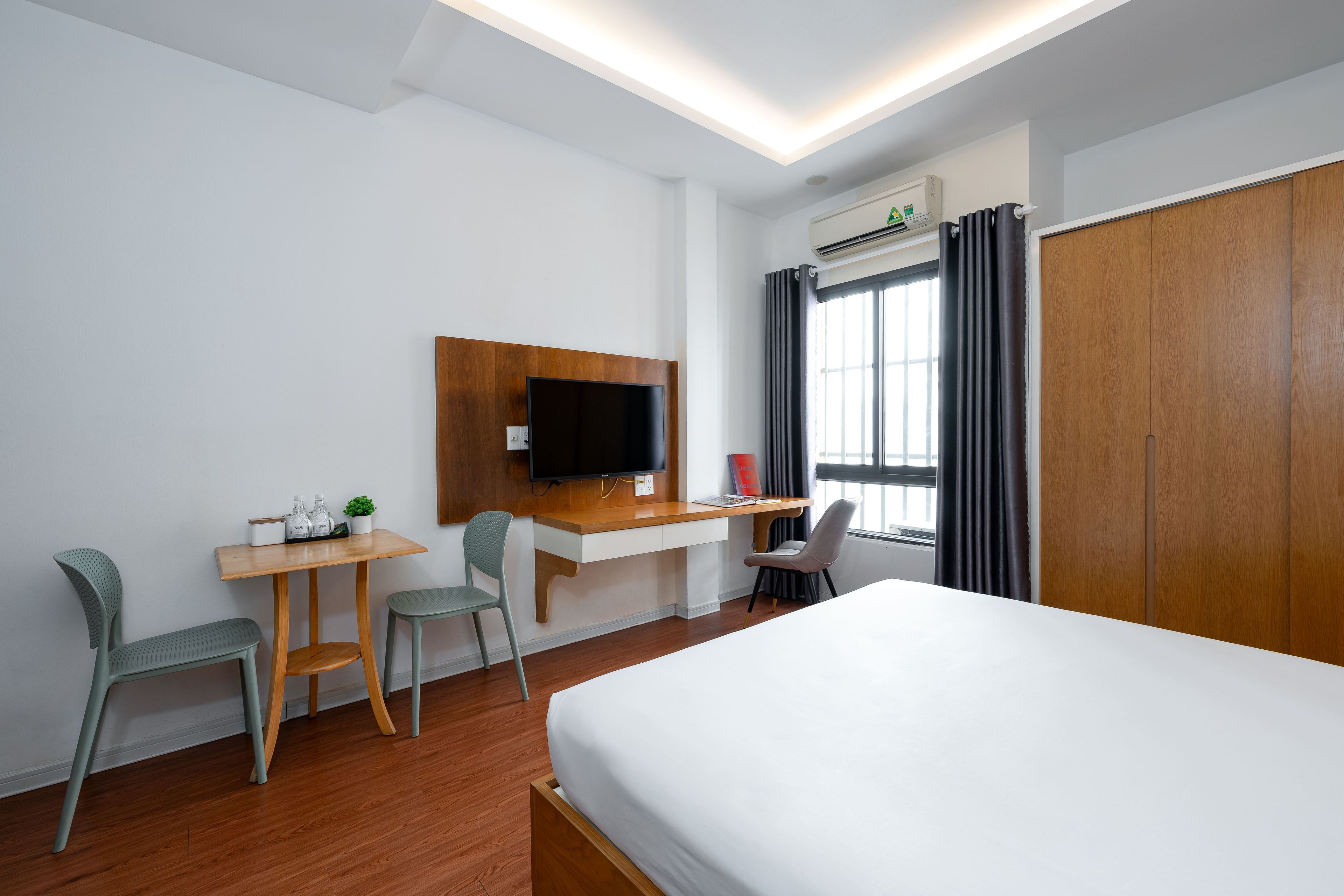 Une chambre d’hôtel comprenant un lit, un bureau avec une chaise, une télévision et une armoire.