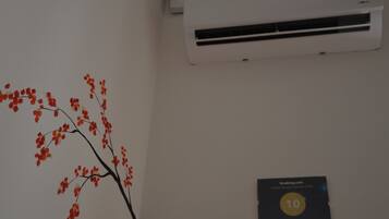A wall with a red and black branch decoration, a thermostat set to 21 degrees, and a plaque indicating a guest award.