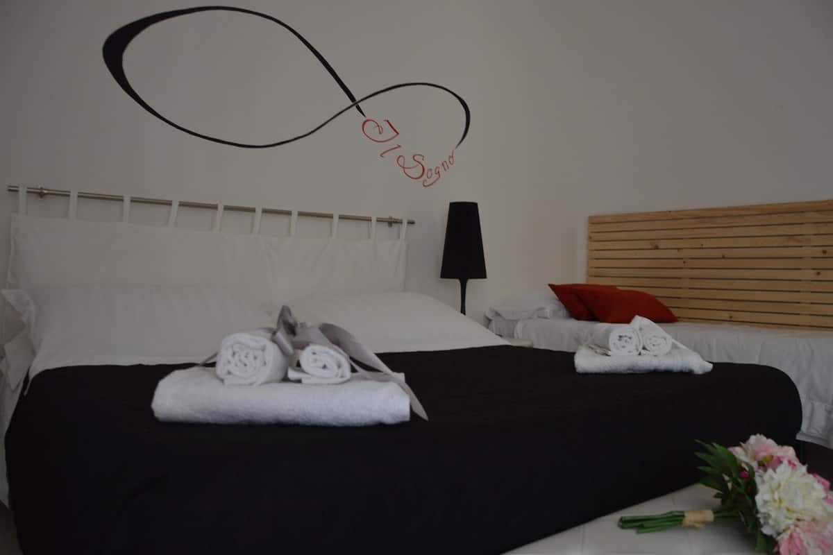 A hotel room with a bed, a black lamp, and a wall decoration.