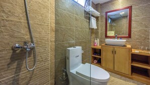 A bathroom with a toilet, a sink, a shower, and a mirror.