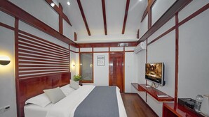 A modern bedroom with a wooden bed, a flat-screen TV, and a bedside table with a remote control. - Lijiang Tongfu Inn (Lijiang)
