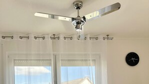 A dining area with a round table and four chairs, a ceiling fan, and a view of buildings through large windows. - Sun oasis in Sigmaringen (Sigmaringen)