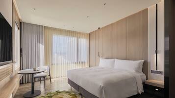 A modern hotel room with a large bed, a small round table, and a seating area.