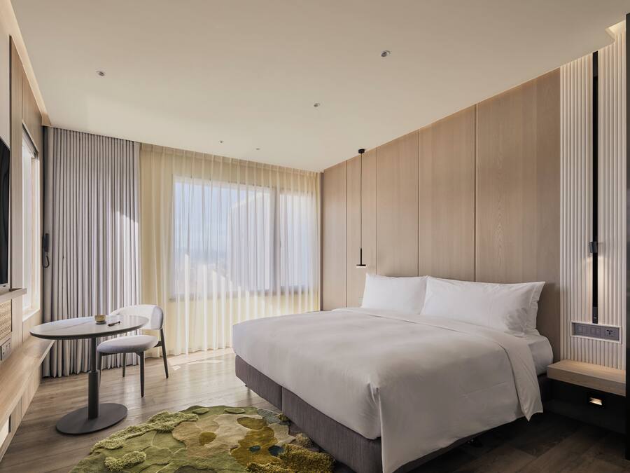 A modern hotel room with a large bed, a small round table, and a seating area.