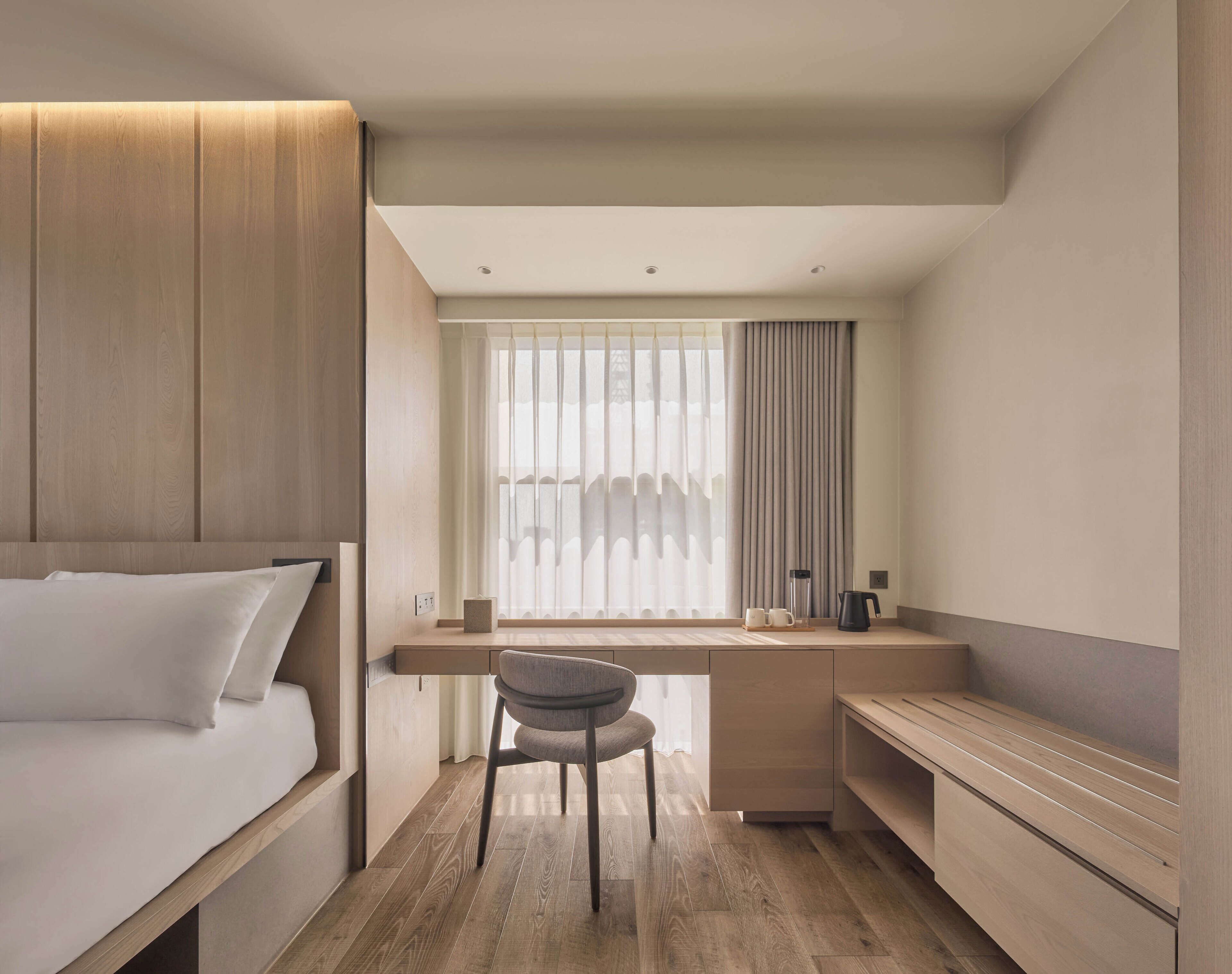 Una habitación de hotel moderna con cama, escritorio, silla y televisión.