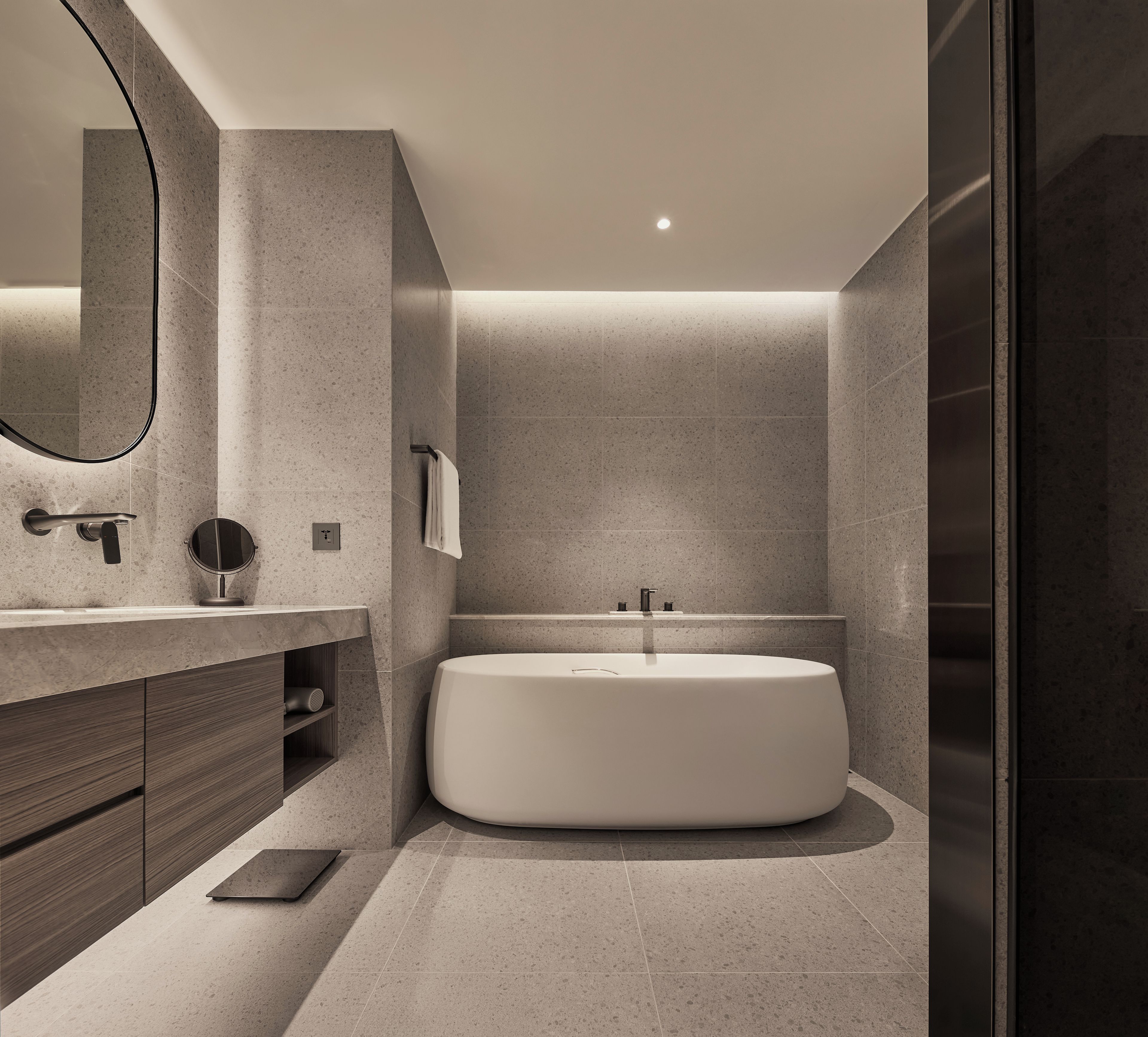 A modern bathroom with a freestanding bathtub, a large mirror, and a vanity with a towel rack.