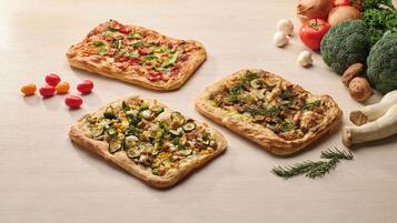 Drie pizza's met verschillende toppings op een houten tafel.