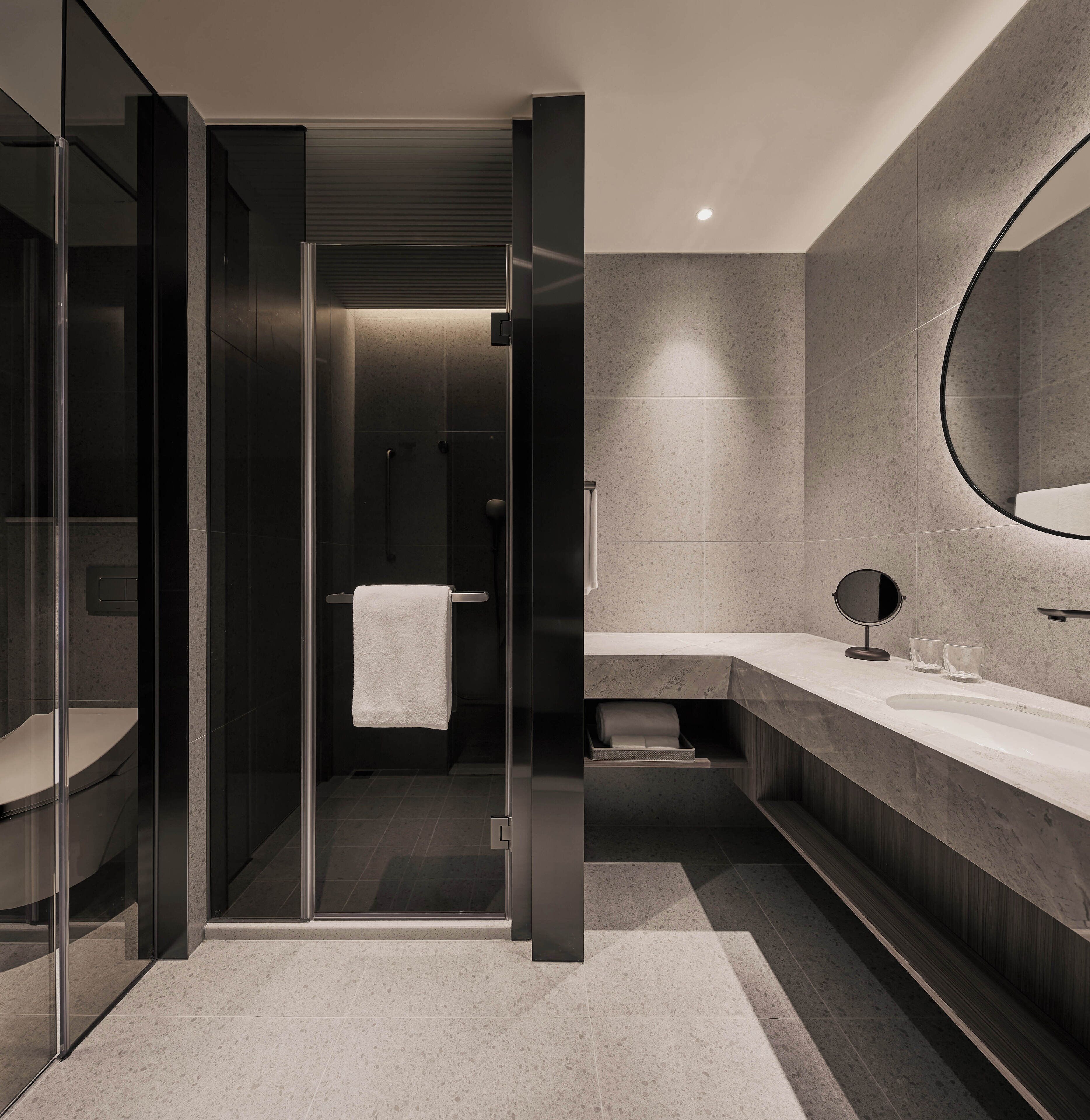 A modern bathroom with a glass-enclosed shower, a vanity with a mirror, and a towel rack.