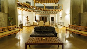Un intérieur spacieux avec un banc en bois, un canapé en cuir noir et une table en bois.