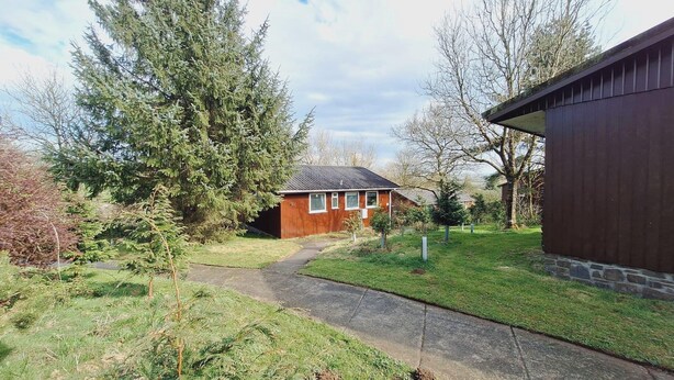 Une petite maison avec une allée pavée menant à la porte d’entrée.
