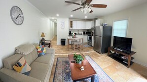 A living room with a sofa, coffee table, and a TV. There is a kitchen in the background with a refrigerator and a microwave. - Renovated 2 Bedroom  in Durham!  New listing but experienced Superhost! (Durham)