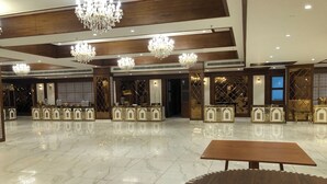 A spacious lobby with a polished marble floor, elegant chandeliers, and ornate reception counters. - Rosastays Hansi (Hansi)