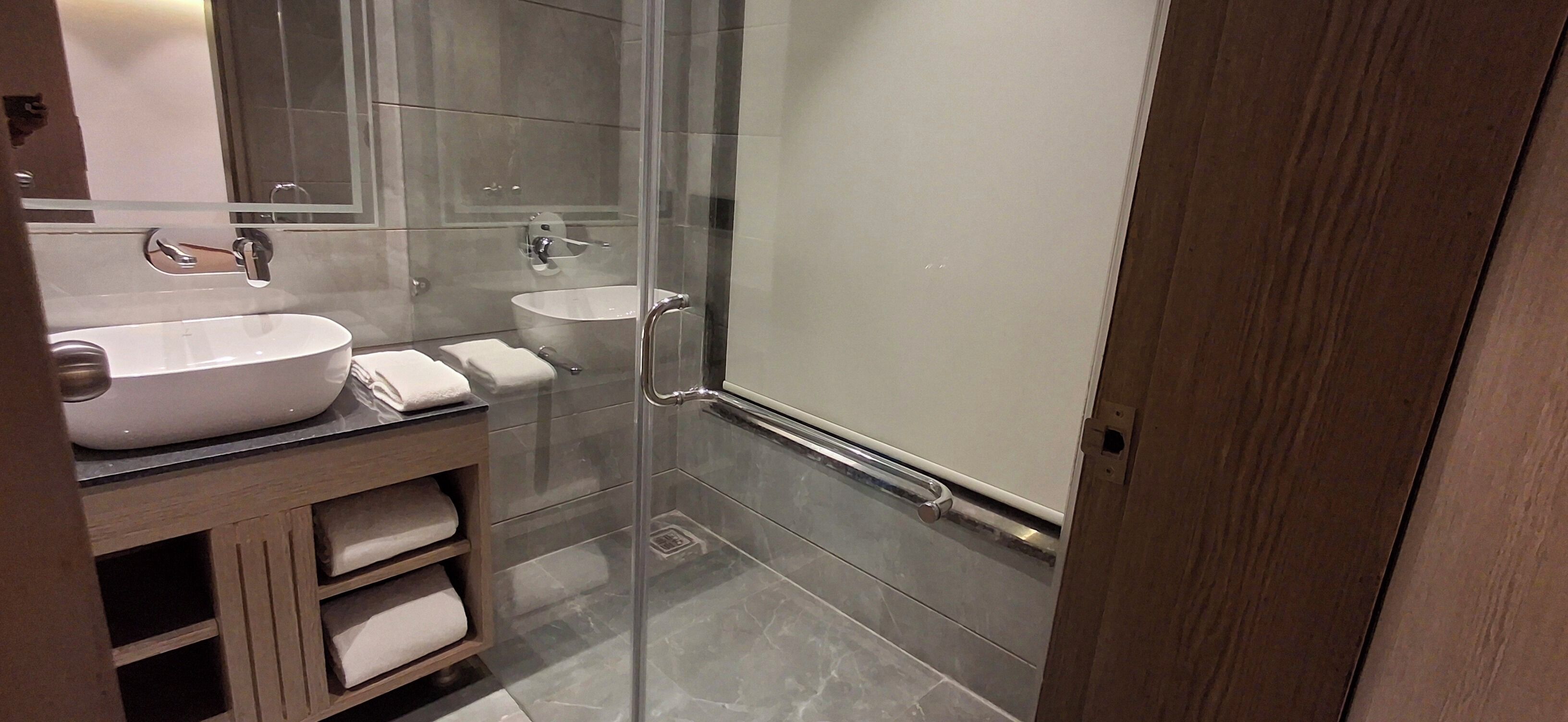 Une salle de bain moderne avec une douche à parois de verre, un lavabo et un meuble-lavabo agrémenté de serviettes.