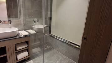Un baño moderno con cabina de ducha de vidrio, un lavabo y un mueble de tocador con toallas.