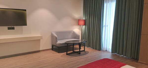 A modern room with a flat-screen TV mounted on the wall, a grey armchair, a small round table, and a red rug on the floor. - Rosastays Hansi (Hansi)