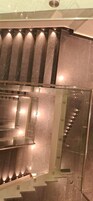 Un interior moderno con barandilla de vidrio y suelo reflectante, que sugiere un diseño contemporáneo.