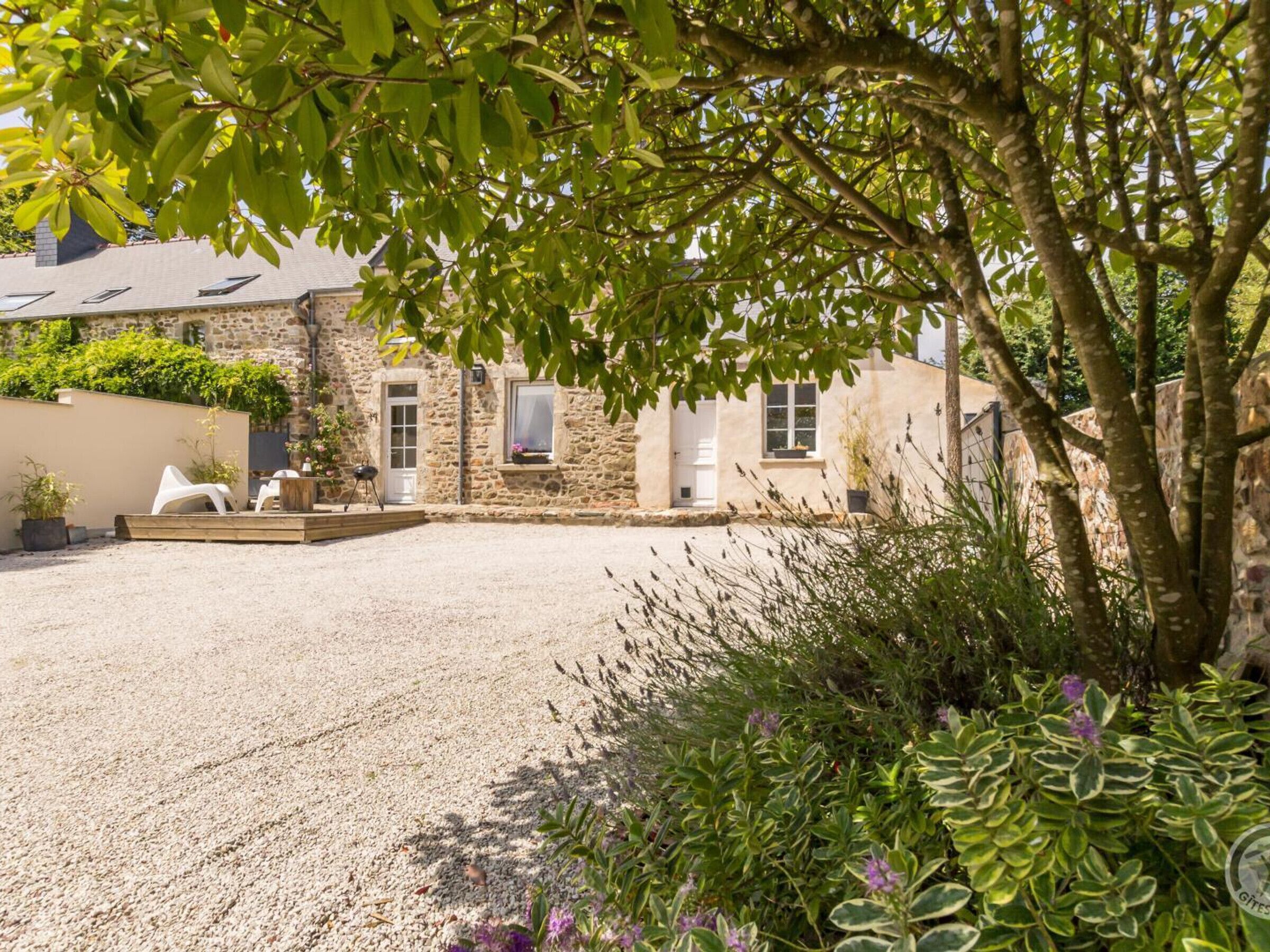A stone building with a gravel driveway, outdoor seating, and potted plants.
