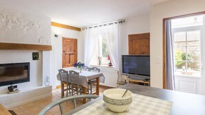 Un espacio habitable compacto con comedor, televisor y vista al exterior.