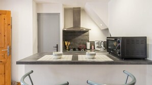 Una cocina compacta con una isla central, dos taburetes de bar, un microondas y una estufa.
