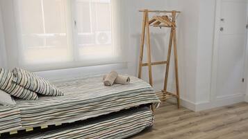 Ein Schlafzimmer mit einem Bett, einem Wäscheständer aus Holz und einem Fenster.