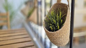 A woven basket with green plants hanging from a metal railing.