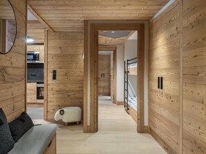 Um interior em madeira com sofá, um banquinho em formato de ovelha e uma cama beliche.