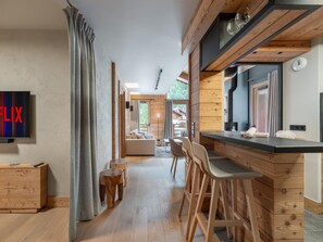 Um interior moderno com área de bar de madeira, sofá e uma televisão exibindo a palavra "FLIX".