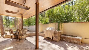 An outdoor patio with a brick floor, wooden ceiling, and a table with chairs. - Broadmoor Retreat Luxe European Style Hot Tub (Colorado Springs)