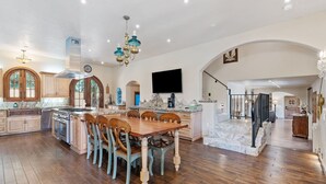 A spacious kitchen with wooden cabinets, a central island, and a dining area with chairs. - Broadmoor Retreat Luxe European Style Hot Tub (Colorado Springs)