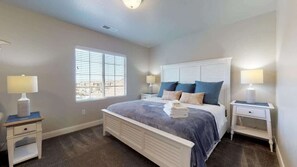 A bedroom with a bed, two bedside tables, a window, and a view. - Huge Pool & Hot Tub | By Zion & St George | 1902SH (Washington)
