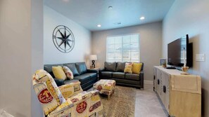 A living room with a sofa set, a television, and a decorative wall piece. - Huge Pool & Hot Tub | By Zion & St George | 1902SH (Washington)
