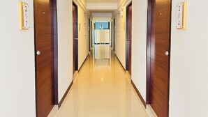 A hotel corridor with wooden doors, numbered signs, and a shiny tiled floor. - Belvilla Chiangmai near Lanna Hospital (Chiang Mai)