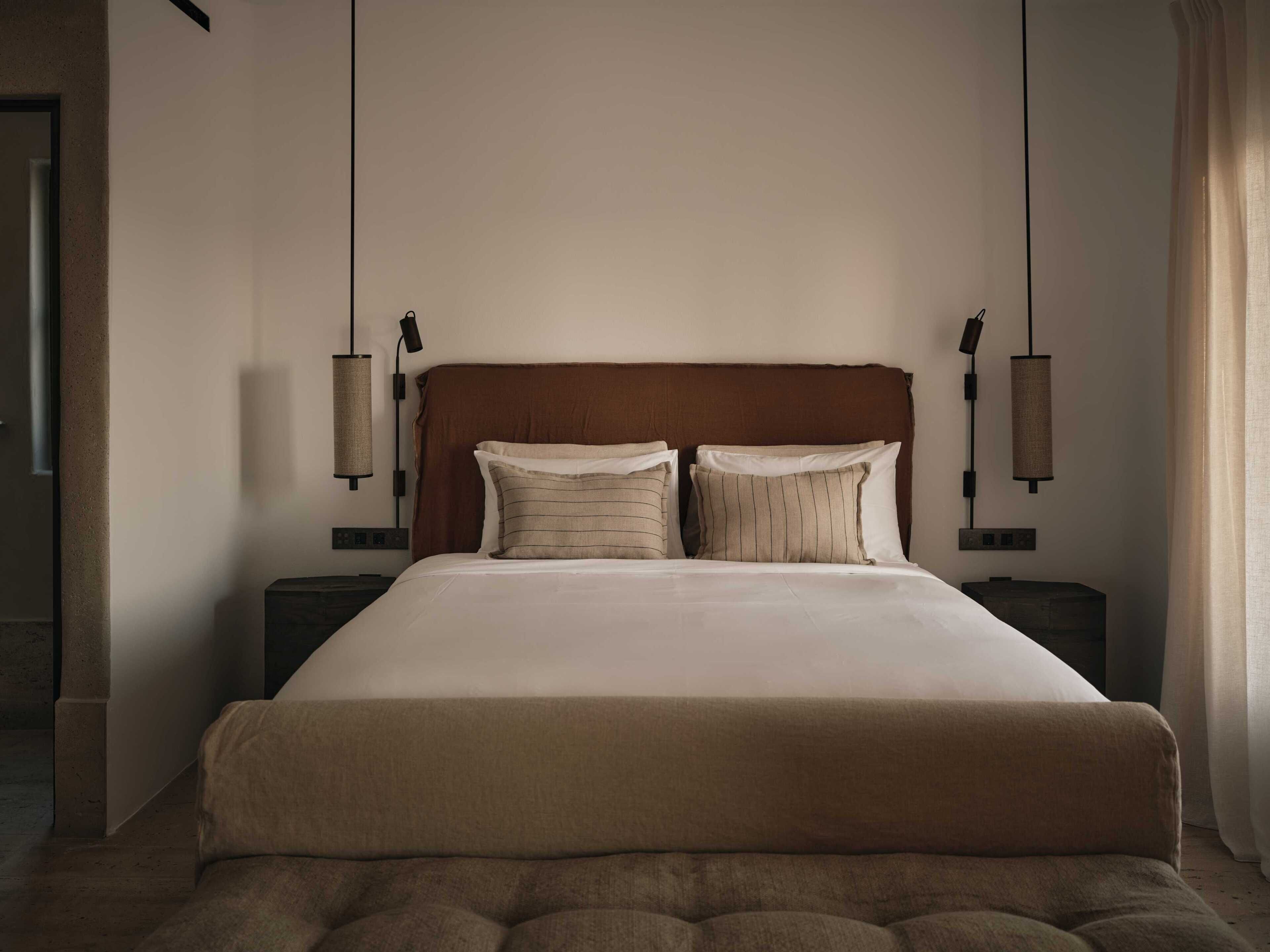 A large bed with a wooden headboard, two bedside tables, and two wall-mounted lamps.