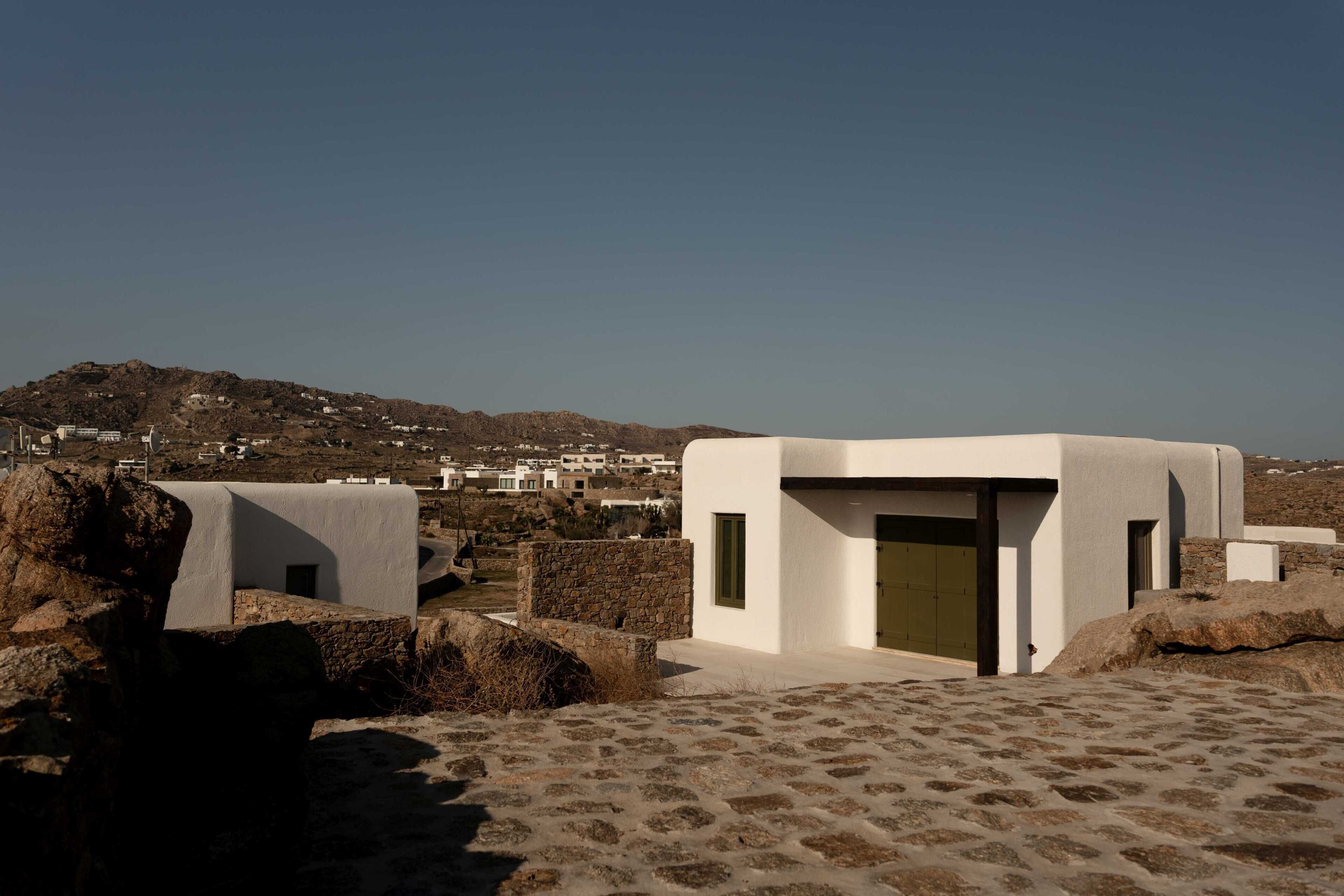A modern building with a flat roof, a stone wall, and a clear view of a distant town.