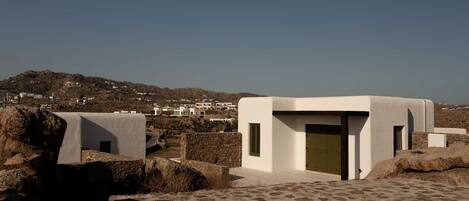 A modern building with a flat roof, a stone wall, and a clear view of a distant town.