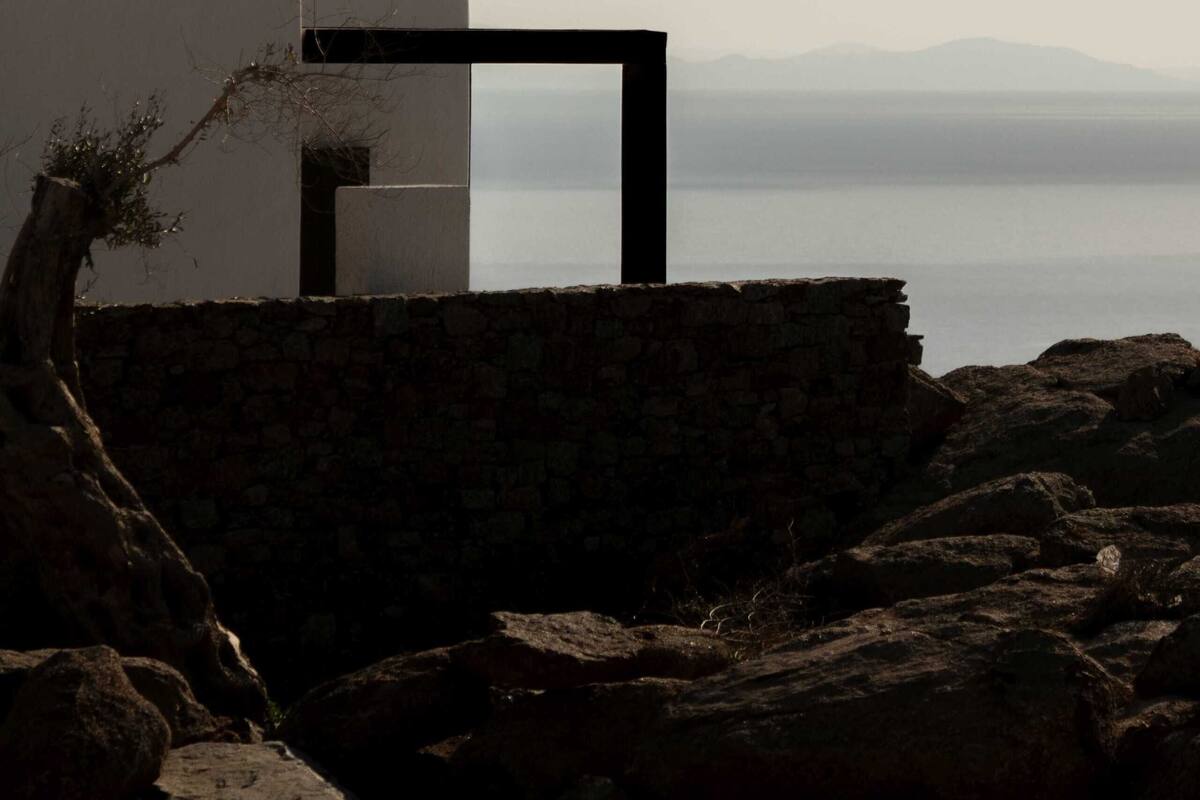 A modern building with a stone wall and a view of the sea.