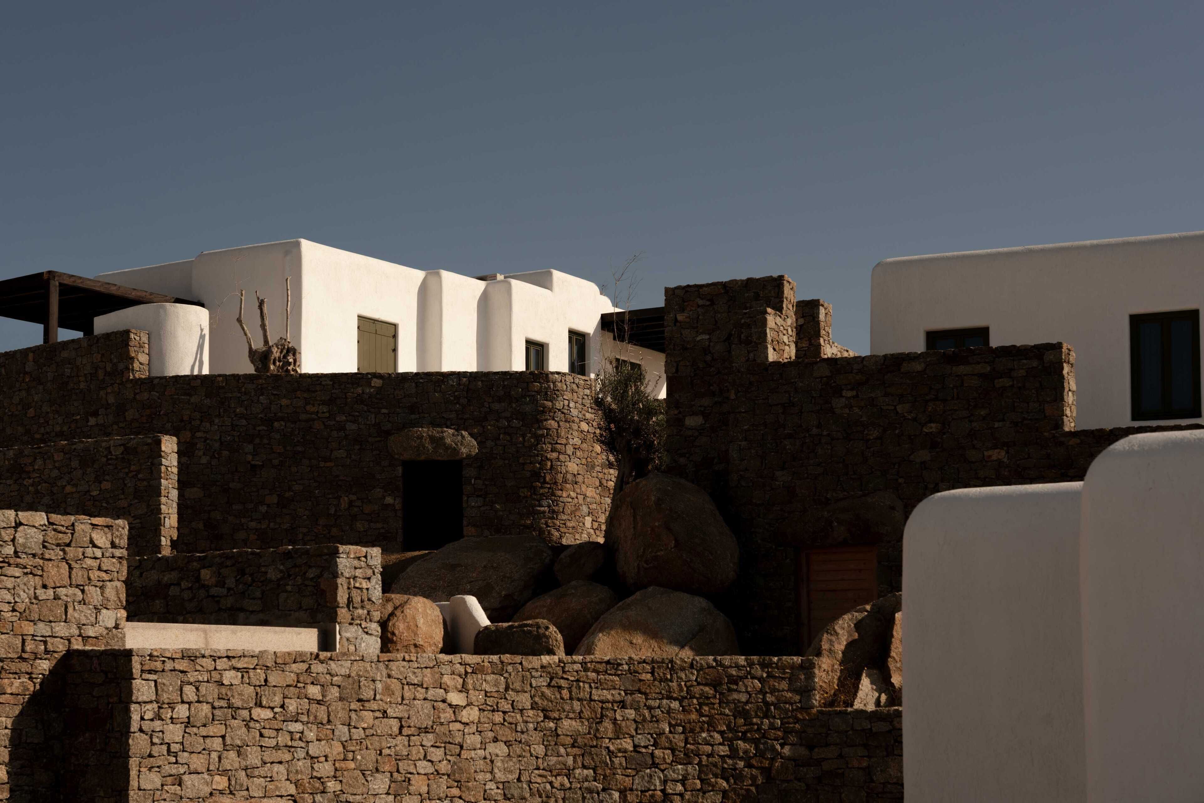 Un edificio de paredes blancas y estructuras de piedra, que incluye una pared de piedra y un ventanal pequeño.