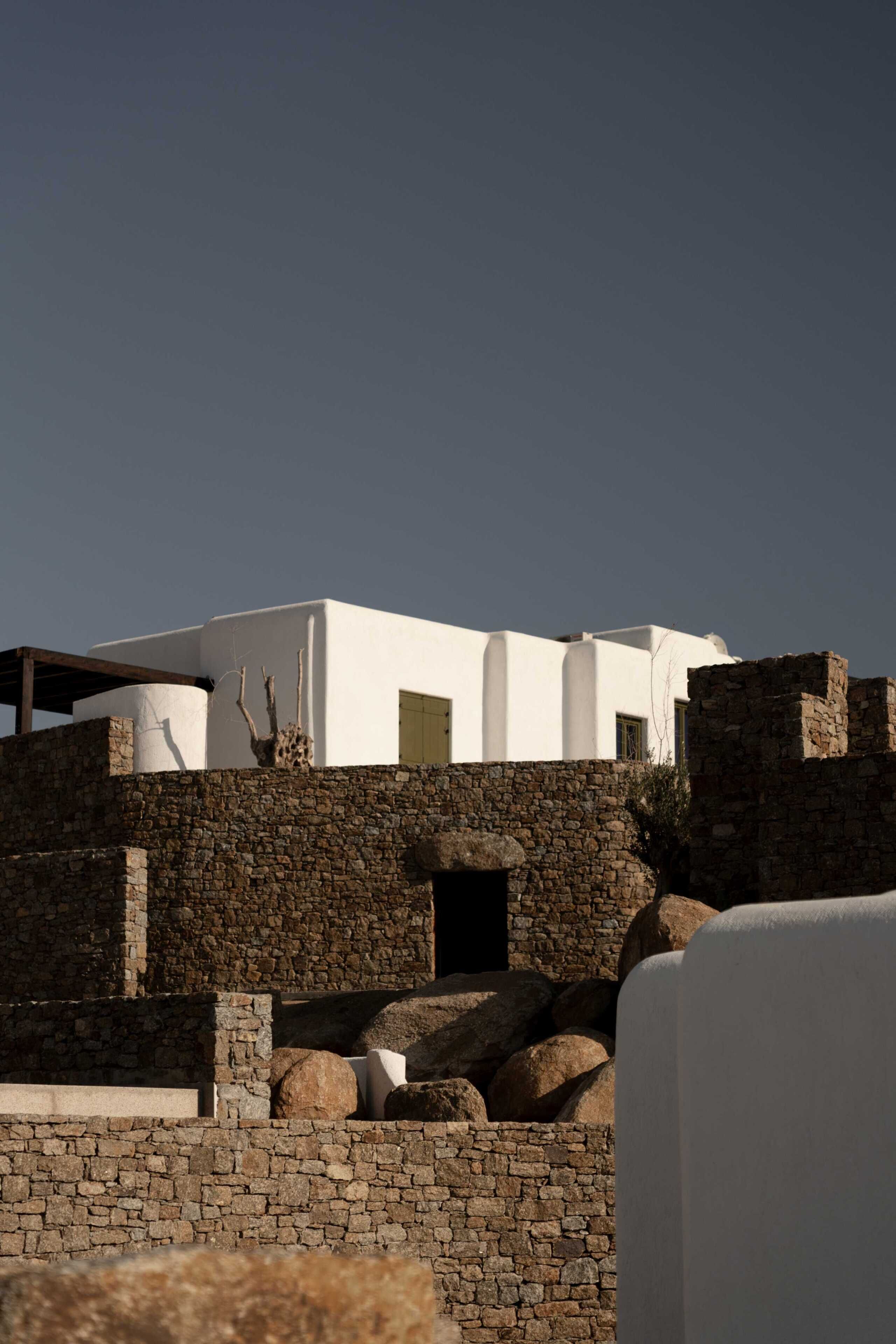Un edificio blanco con un muro de piedra y una entrada.